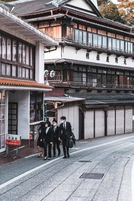 Group of business professionals walking in a Japanese street with traditional buildings.
