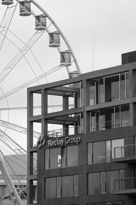 Black and white shot of an urban office building with a Ferris wheel in the background.