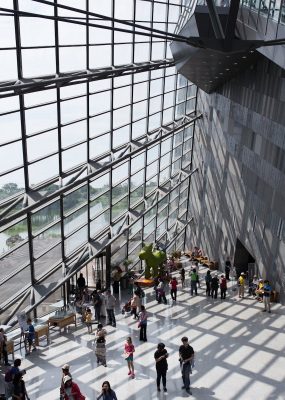 A modern interior lobby with people gathered near large glass windows.